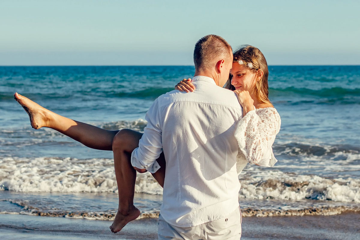 man-holding-a-woman-in-his-hands-on-the-beach