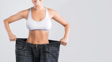 woman-showing-result-after-weight-loss-wearing-on-old-jeans-photo